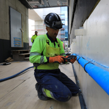 Pracownik budowlany zajmuje się mocowaniem niebieskich rur w obiekcie