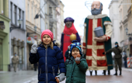 Dwoje małych dzieci stoi na ulicy Szerokiej, w tle figury trzech króli