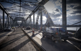 Samochody jadące przez rozbudowywany most w promieniach słońca