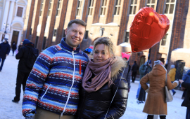 Na zdjęciu kobieta trzyma balon w kształcie serca obok obejmuje ją mężczyzna
