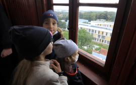 Na zdjęciu: troje dzieci patrzy przez okno w wieży ciśnień
