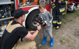 Strażak pokazuje małemu chłopcu sprzęt strażacki