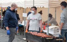 Dwaj mężczyźni - klient i sprzedawca przy stoisku z grillowanymi kiełbaskami