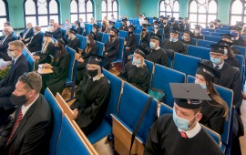 Absolwenci w biretach siedzą w ławkach auli Kolegium Jagiellońskiego