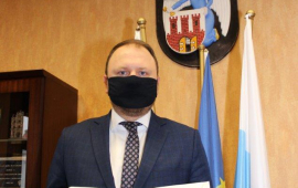 Paweł Gulewski pokazuje akt nominacji na zastępce prezydenta, w tle na scianie wisi herb Torunia