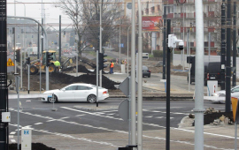 Biały samochód jedzie przez wyremontowany plac Niepodległości.