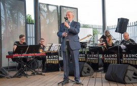 Organizator, Henryk Giza, otwiera koncert, w tle siedzą muzycy