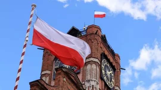 Flaga Polski powiewa na tle wieży Ratusza Staromiejskiego.