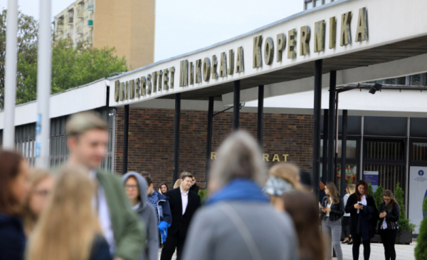 Zdjęcie przedstawia tłum studentów na kampusie Uniwersytetu Mikołaja Kopernika w Toruniu