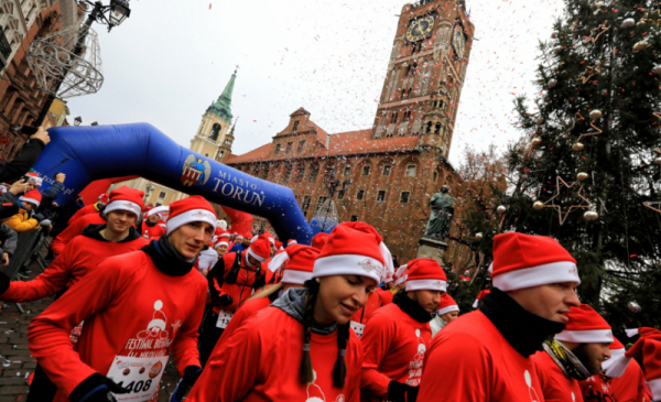 Na zdjęciu: uczestnicy biegu w strojach Świętego Mikołaja stoją na linii startu na Rynku Staromiejskim, w tle ratusz
