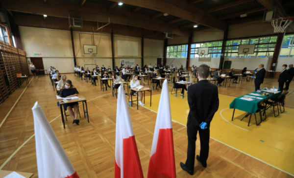 Sala gimnastyczna, w której rozszadzeni w bezpiecznych odległościach uczniowie piszą egzamin maturalny 