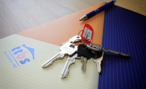 Na zdjęciu widać klucze do mieszkania, długopis oraz teczkę z dokumentami