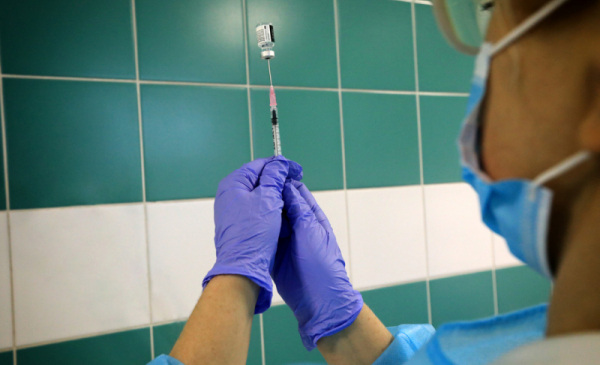 Pielegniarka ze strzykawką pobiera zawartość szczepionki z buteleczki