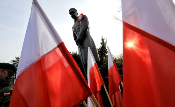 Na zdjęciu: pomnik marszałka Józefa Piłsudskiego widziany pomiędzy biało-czerwonymi flagami