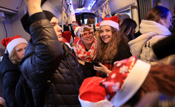 Na zdjęciu: pasażerowie w świątecznym tramwaju, wśród nich osoby w czapkach mikołaja