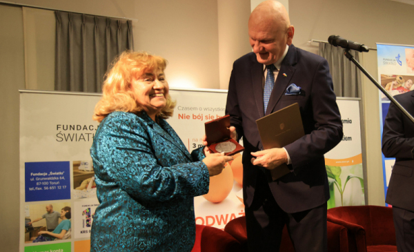 Uśmiechnięta Nina Mirończuk odbiera medal z rąk prezydenta Torunia 