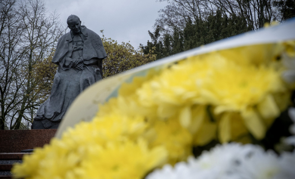 Na zdjęciu żółto-białe kwiaty, w tle pomnij papieża Jana Pawła II