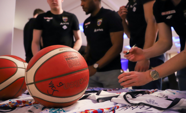 Na zdjęciu: zawodnicy Twardych Pierników podpisują koszulki, na pierwszym planie piłka koszykarska
