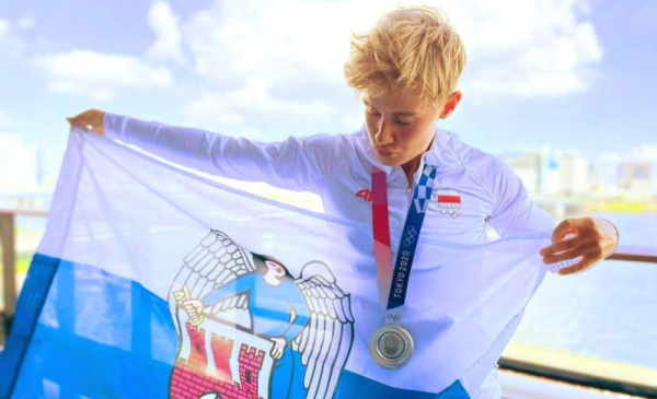 Toruńska wioślarka Katarzyna Zillmann z medalem olimpijskim i flagą Torunia.