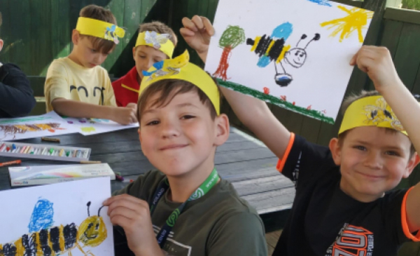 Na zdjęciu przedszkolaki trzymają prace z narysowanymi pszczołami