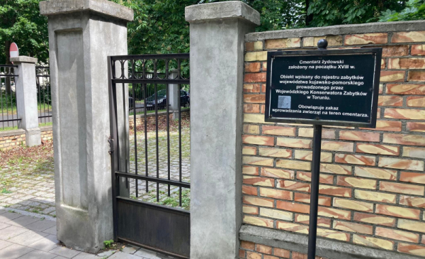 Mur i tablica w wejściu cmentarza żydowskiego w Toruniu