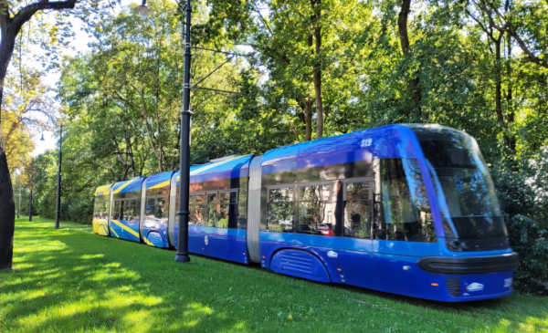 Zdjęcie przedstawia tramwaj przejeżdżający nowym zielonym torowiskiem