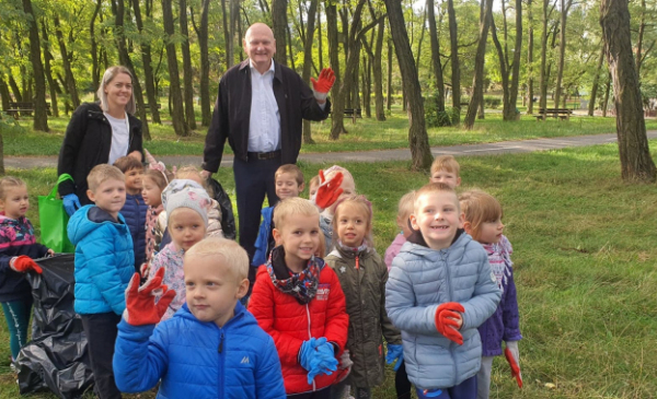 Na zdjęciu: prezydent Michał Zaleski wraz z przedszkolakami machają dłońmi w rękawicach po sprzątaniu parku