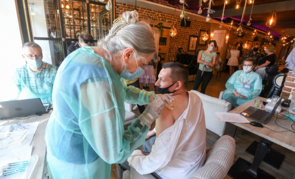 Na zdjęciu pielęgniarka szczepi mężczyznę w restauracji