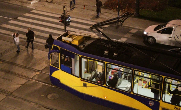 Na zdjęciu tramwaj stoi na skrzyżowaniu wieczorem