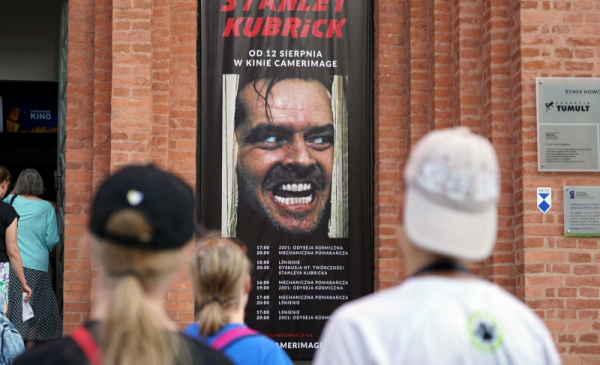 Na zdjęciu osoby wchodzą do kina Camerimage, na fasadzie budynku baner przeglądu z kadrem z filmu Lśnienie