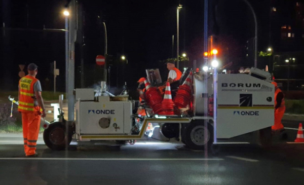 Na zdjęciu: pracownicy w pomarańczowych ubraniach roboczych maluną pasy na jezdni nocą