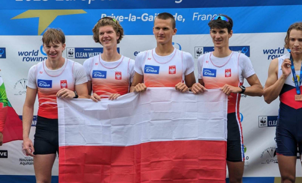 Na zdjęciu: zawodnicy z czwórki podwójnej, w tym torunianin, trzymają biało-czerwoną flagę