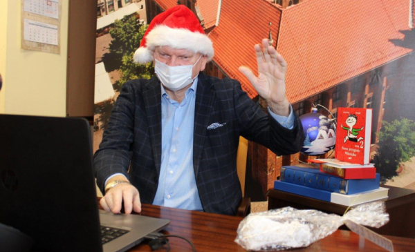 Prezydent Michał Zaleski w czapce Mikołaja macha do uczniów, z którymi połączył się poprzez internet.