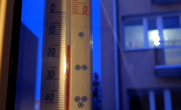 Termometr okienny na tle wieczrnego osiedla