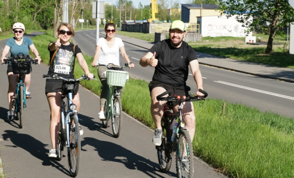 Na zdjęciu uśmiechające się osoby jadą na rowerze