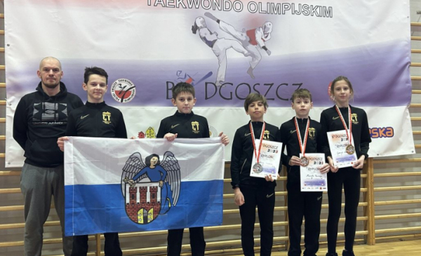 Na zdjęciu: pięcioro zawodników klubu Centuria Toruń stoi z medalami, dyplomami i flagą z herbem Torunia