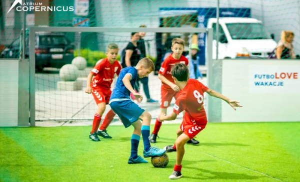Na zdjęciu: chłopcy grają w piłkę nożną na zielonej murawie boiska