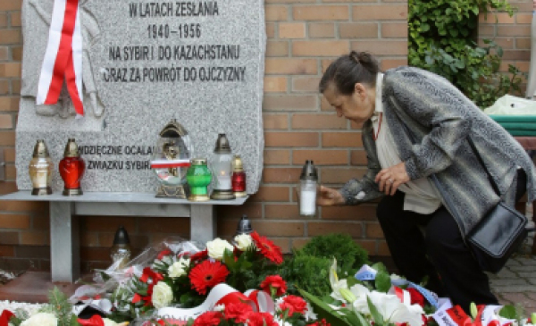 Kobieta pod tablicą Matki Polki Sybiraczki przy kościele na Koniuchach