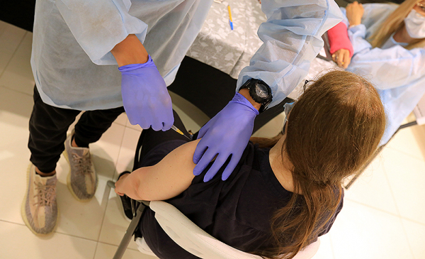Na zdjęciu młoda osoba szczepiąca się przeciw Covid-19