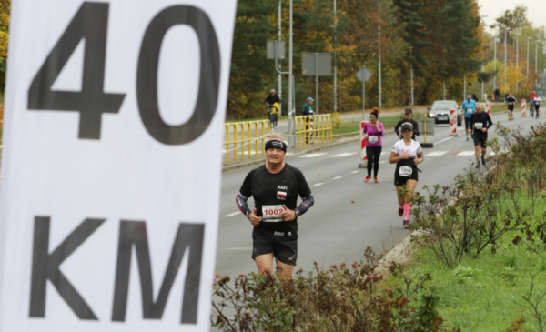 Na zdjęciu: fragment flagi informującej o 40. kilometrze trasy maratonu toruńskiego, w tle widać biegaczy