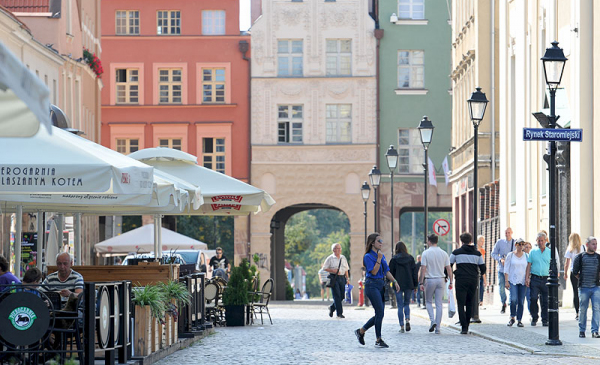 Ulica Różana w Toruniu latem, widok na ogrodek restauracji, idących ludzi, kamienice w tle