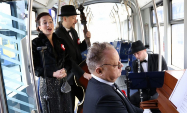Na zdjęciu: w tramwaju wokalistka śpiewa, jeden muzyk gra na kontrabasie, drugi na pianinie