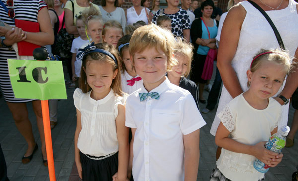 Na zdjęciu: ubrany na galowo uczeń klasy pierwszej, obok tabliczka - klasa 1 c