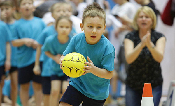 Na zdjęciu widać rywalizację sportową dzieci - chłopiec rzuca piłką