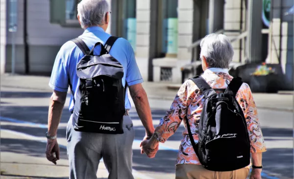 Para seniorów spaceruje po Toruniu trzymając się za ręce.
