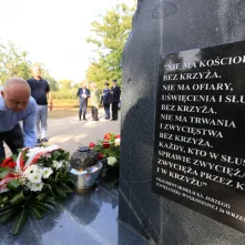 Kwiaty pod pomnikiem ks. Popiełuszki i tablicą Solidarności