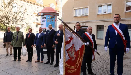 Kwiaty pod pomnikiem ks. Popiełuszki i tablicą Solidarności