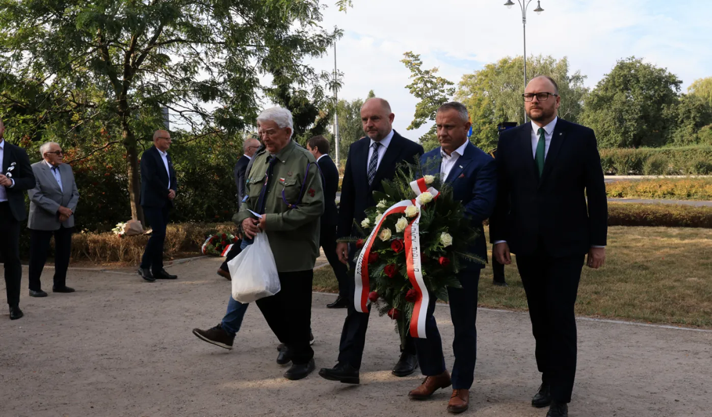 Kwiaty pod pomnikiem ks. Popiełuszki i tablicą Solidarności