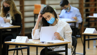 Uczennica w masce pochylona nad kartką papieru