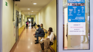 Na zdjęciu osoby czekają na korytarzu na szczepienie